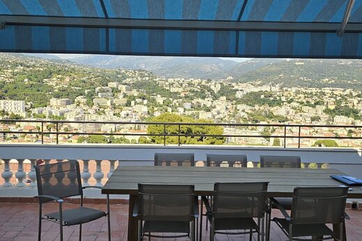 Terrasse sur le toit avec vue sur la ville, auvents à rayures bleues.