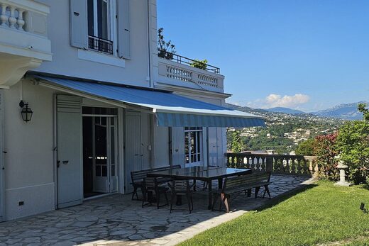 Patio avec table, chaises ; villa Nice, volets bleus.